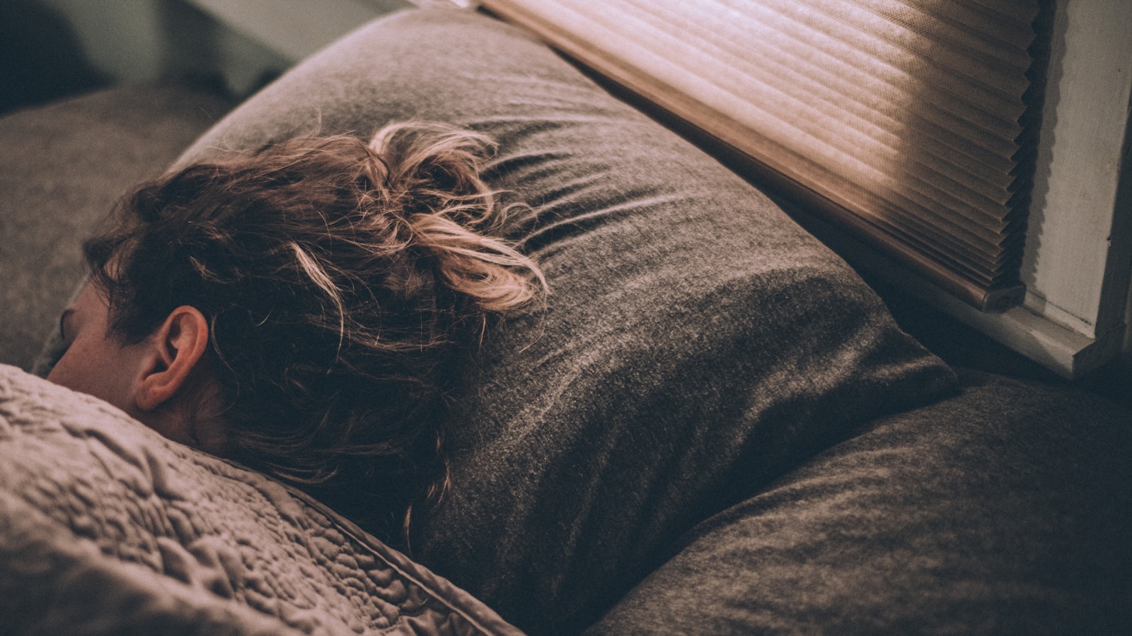 Žena klidně spí v posteli pod přikrývkou — Foto: Greg Pappas / Unsplash