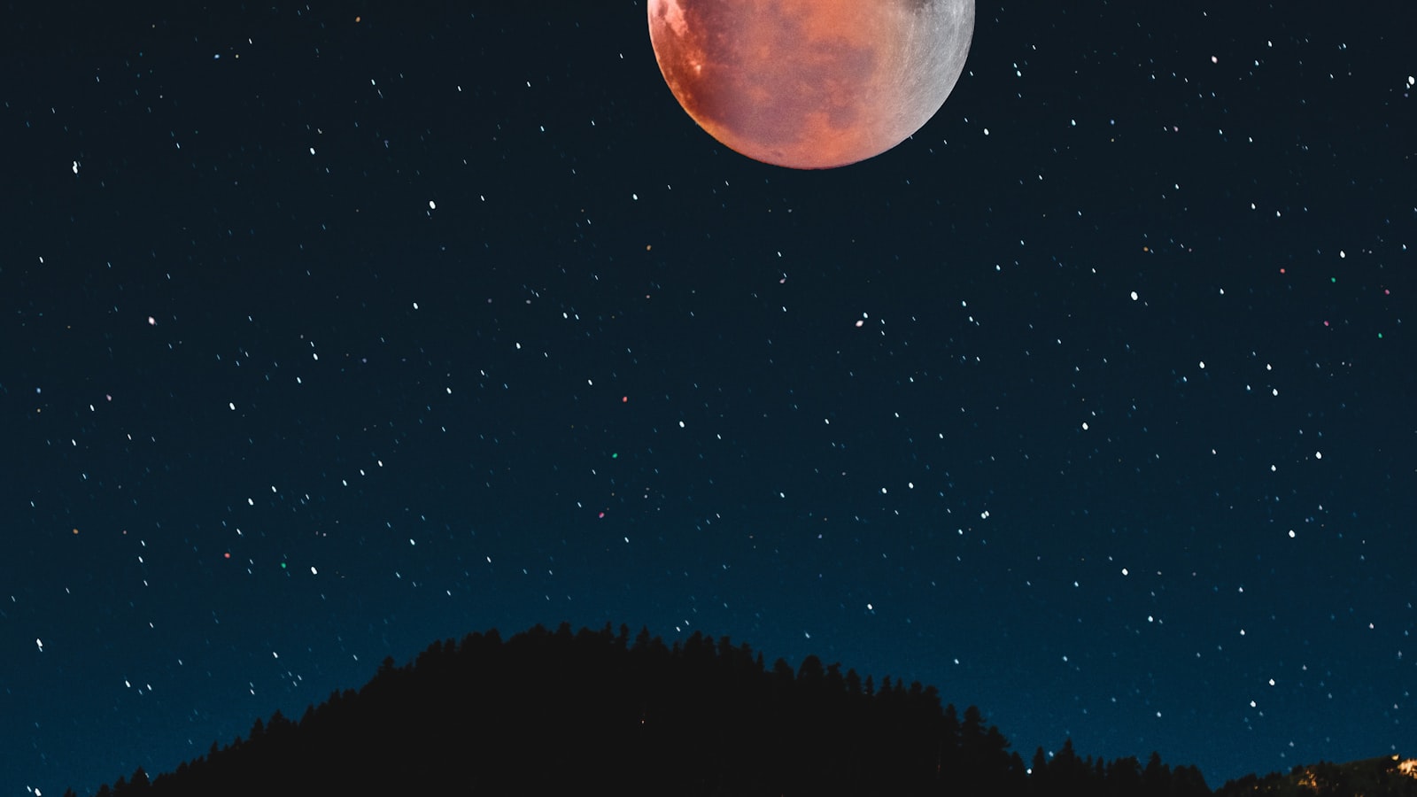 Silueta hory pod úplňkem na noční obloze — Foto: Tim Sessinghaus / Unsplash