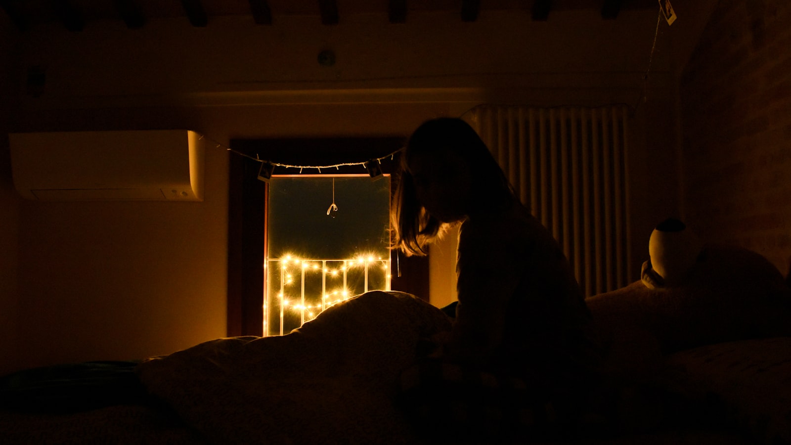 Člověk sedící vzhůru na posteli v tmavém pokoji — Foto: Greta Bartolini / Unsplash