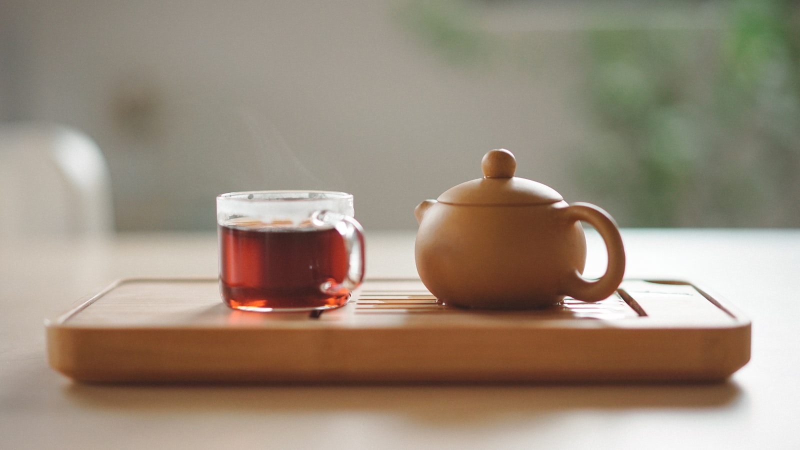 Skleněný šálek bylinného čaje u keramické konvičky — Foto: Manki Kim / Unsplash
