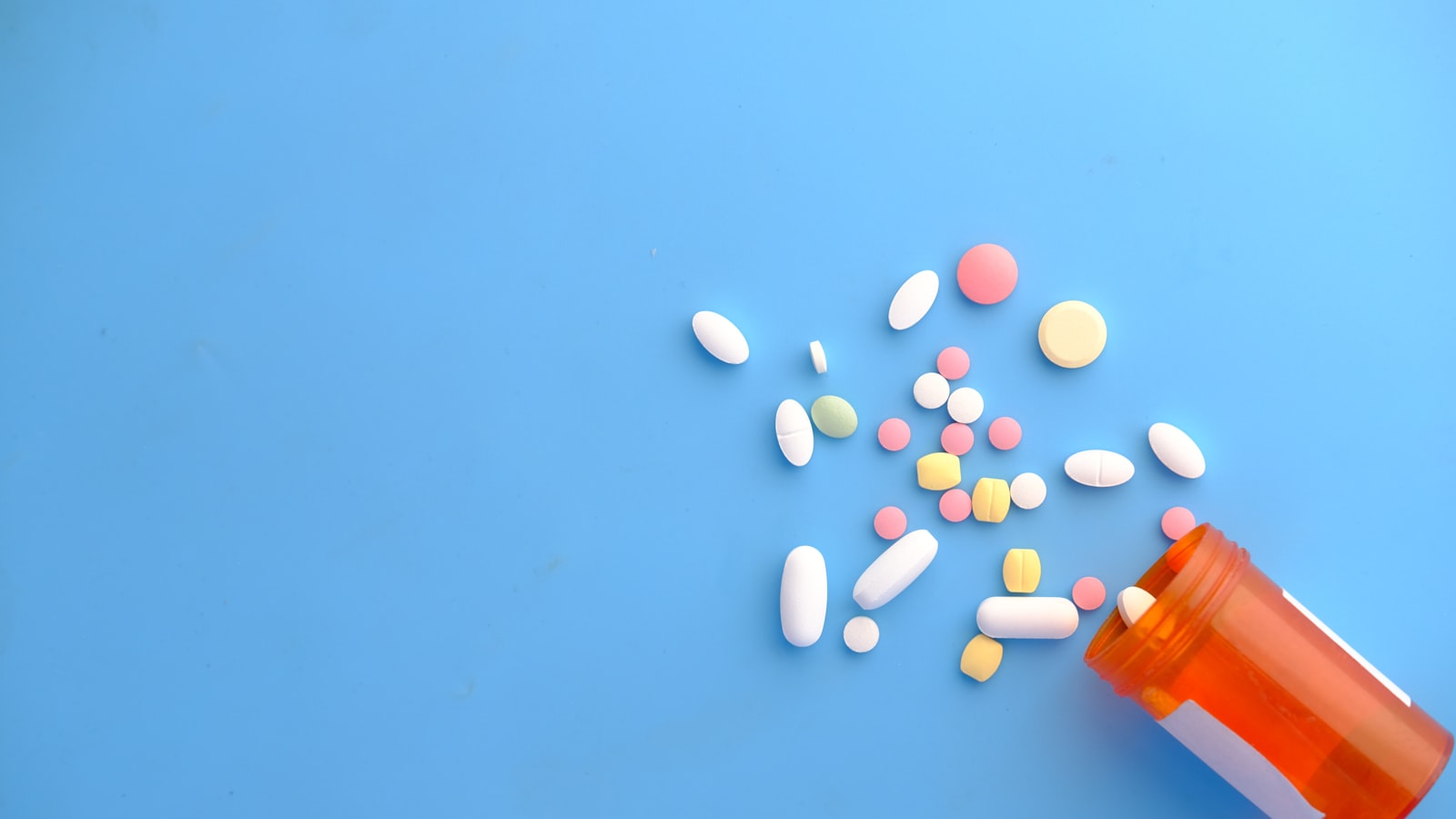 Barevné vitamíny vysypané z oranžové lékovky — Foto: Towfiqu barbhuiya / Unsplash